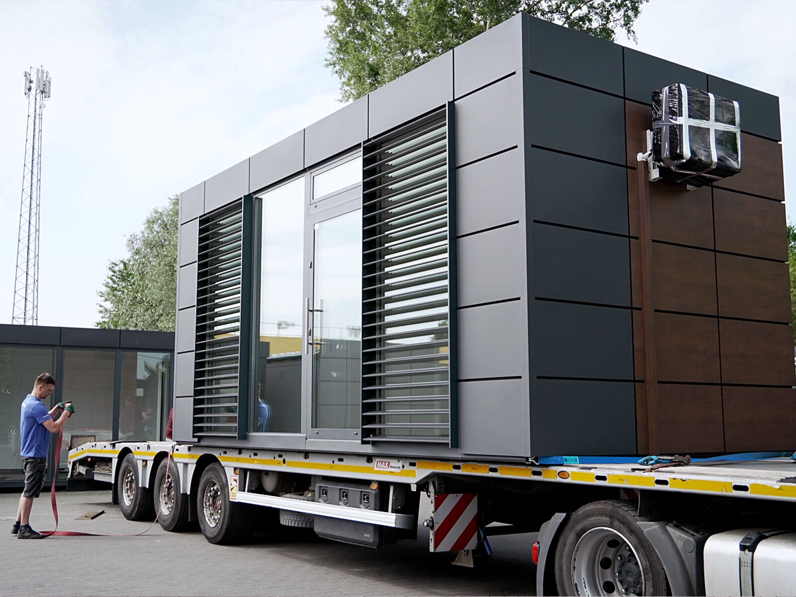 Transport van een moderne kantoorcontainer met metalen gevel op een vrachtwagen      