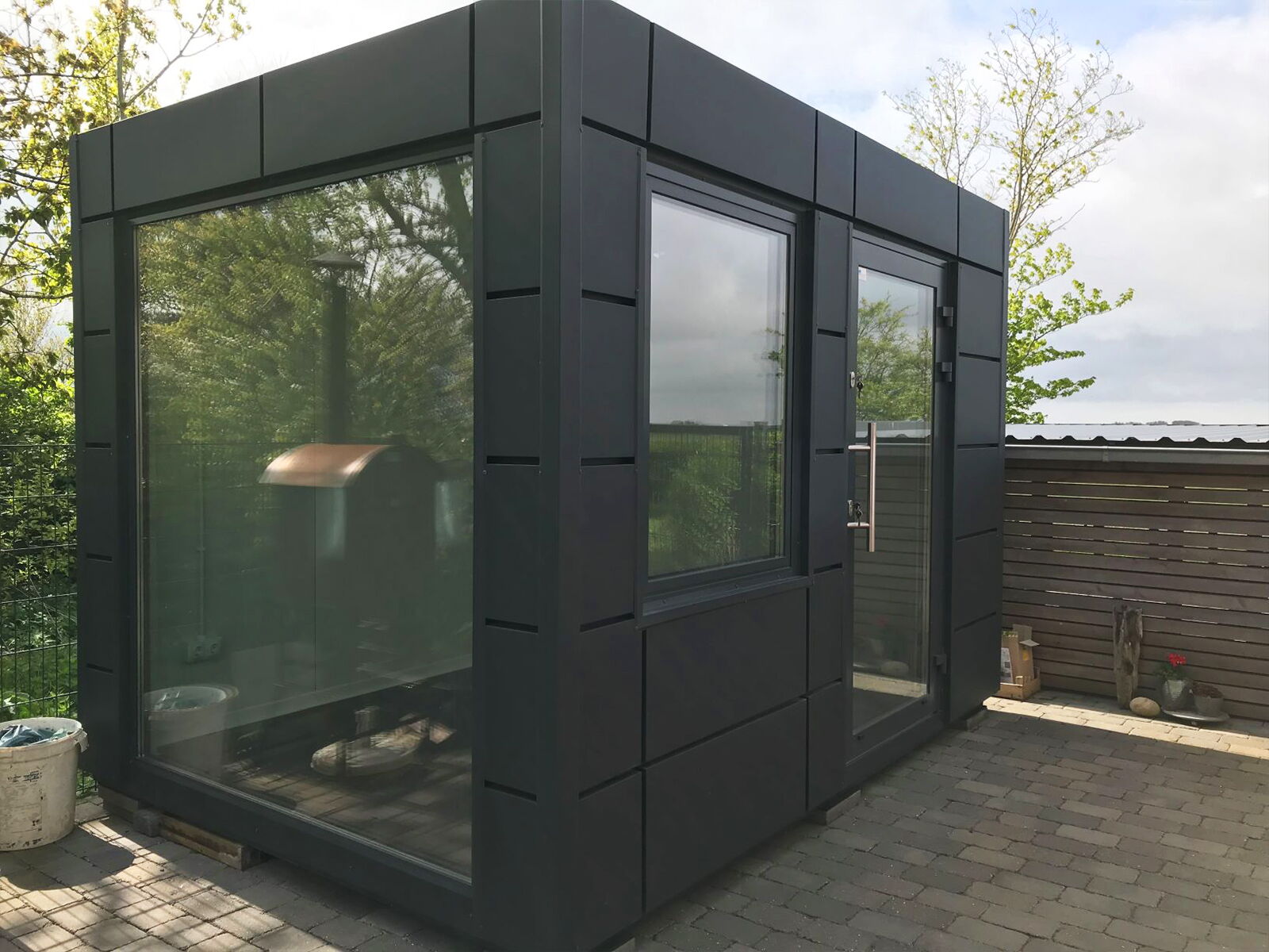 Kleine design-modulcontainer met grote glasvoorkant op terras      